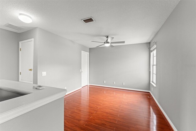 unfurnished room with a textured ceiling, hardwood / wood-style flooring, and ceiling fan