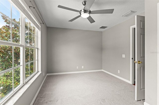 spare room with ceiling fan, light carpet, and a textured ceiling