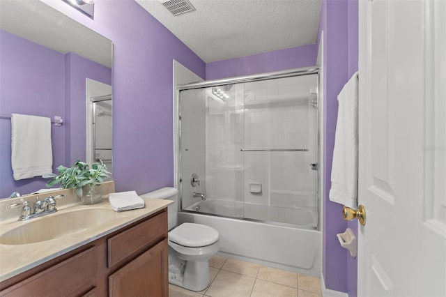 full bathroom with a textured ceiling, vanity, combined bath / shower with glass door, toilet, and tile patterned floors