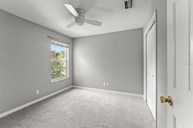 unfurnished bedroom featuring a closet, ceiling fan, light carpet, and a textured ceiling