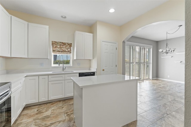 kitchen featuring sink, a kitchen island, a healthy amount of sunlight, white cabinets, and hanging light fixtures