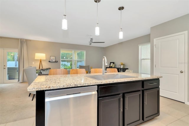 kitchen with ceiling fan, dishwasher, light stone countertops, sink, and a kitchen island with sink