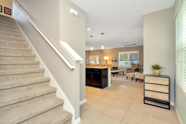 stairway with tile patterned floors, ceiling fan, and sink