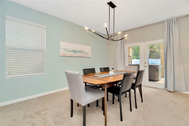 dining space with a notable chandelier, light carpet, and french doors