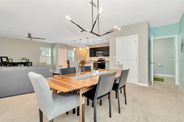 dining space with ceiling fan with notable chandelier and light colored carpet