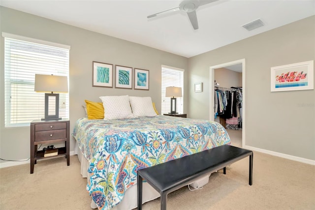 carpeted bedroom with ceiling fan, a spacious closet, multiple windows, and a closet