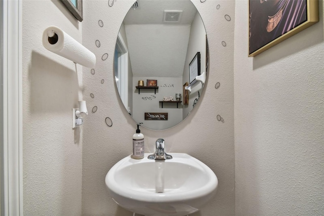 bathroom featuring a textured wall, a sink, and visible vents