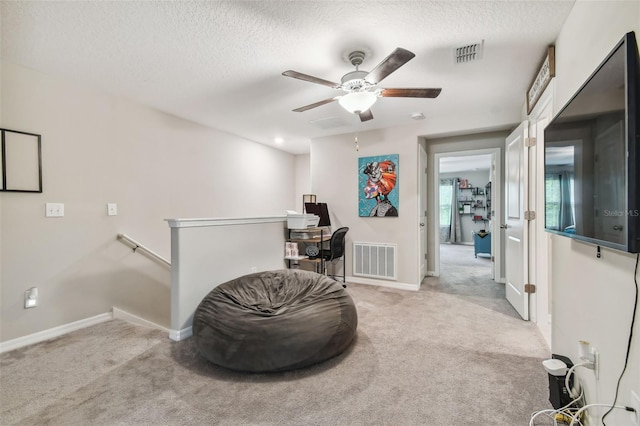 living area featuring light colored carpet, a textured ceiling, and ceiling fan