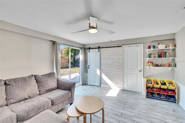 living room with a barn door and ceiling fan