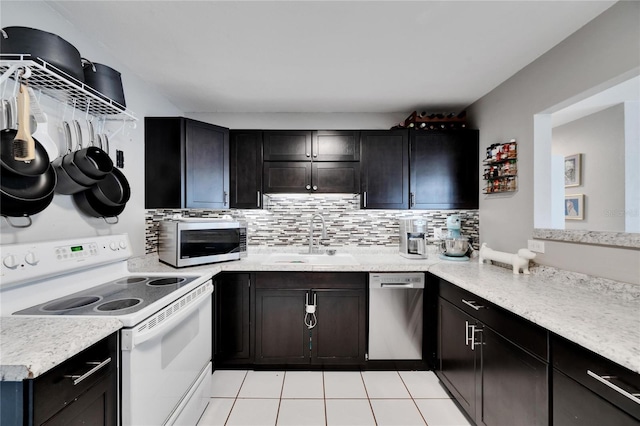 kitchen with sink, tasteful backsplash, light tile patterned flooring, dark brown cabinetry, and stainless steel appliances