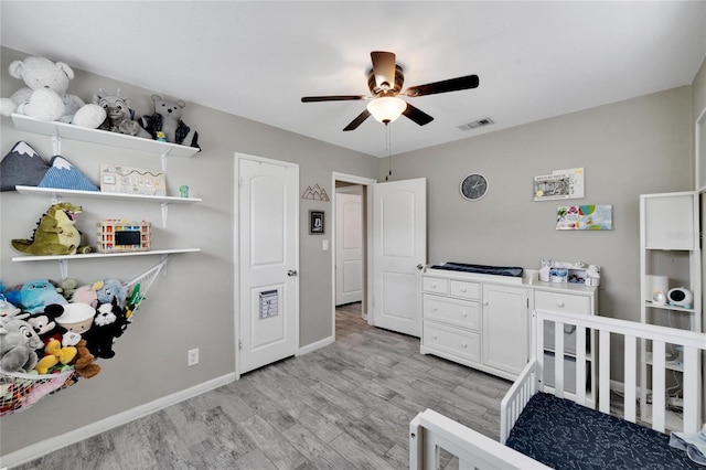 bedroom featuring light hardwood / wood-style flooring, a nursery area, and ceiling fan