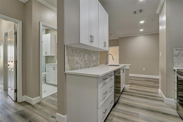 kitchen featuring light countertops, visible vents, ornamental molding, a sink, and dishwasher