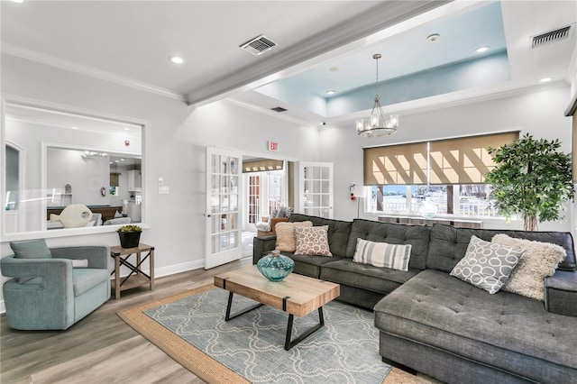 living room with hardwood / wood-style floors, an inviting chandelier, ornamental molding, and french doors