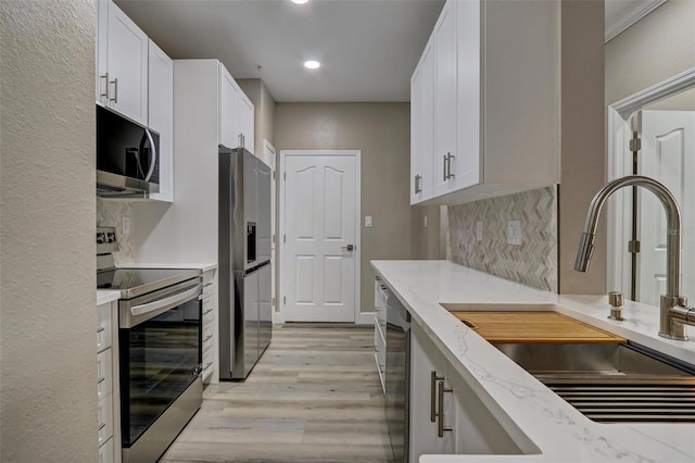 kitchen featuring decorative backsplash, stainless steel appliances, white cabinetry, and sink