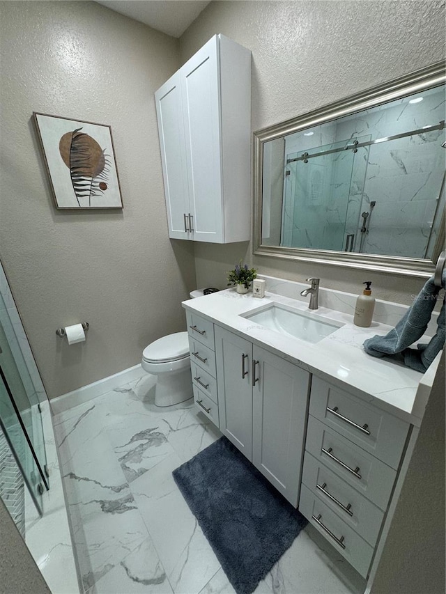 full bathroom with marble finish floor, a marble finish shower, toilet, vanity, and baseboards