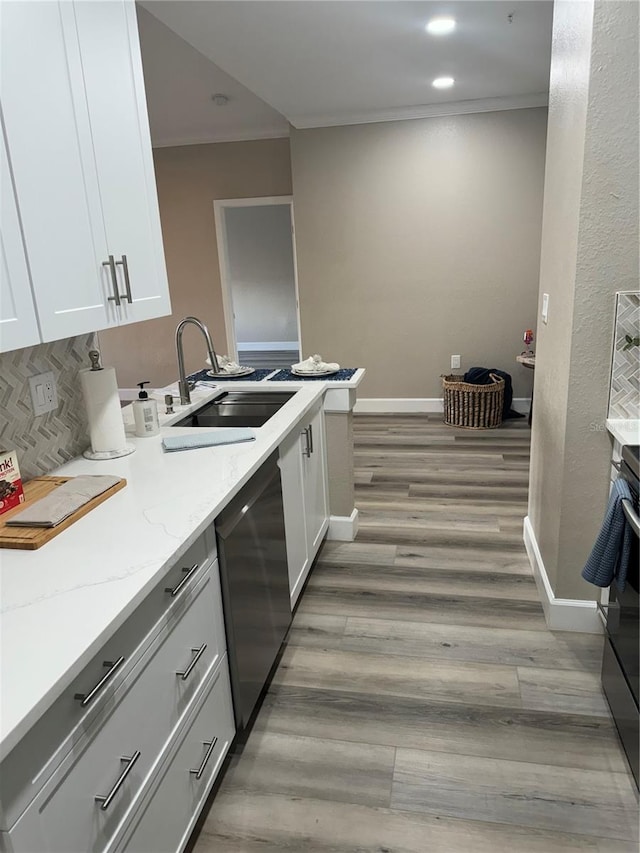 kitchen featuring a sink, white cabinets, ornamental molding, dishwasher, and light wood finished floors