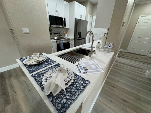 kitchen featuring baseboards, white cabinetry, appliances with stainless steel finishes, and wood finished floors