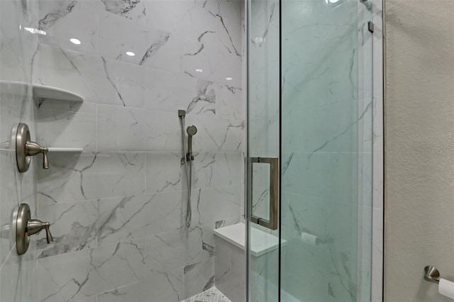 bathroom featuring a textured wall and a marble finish shower