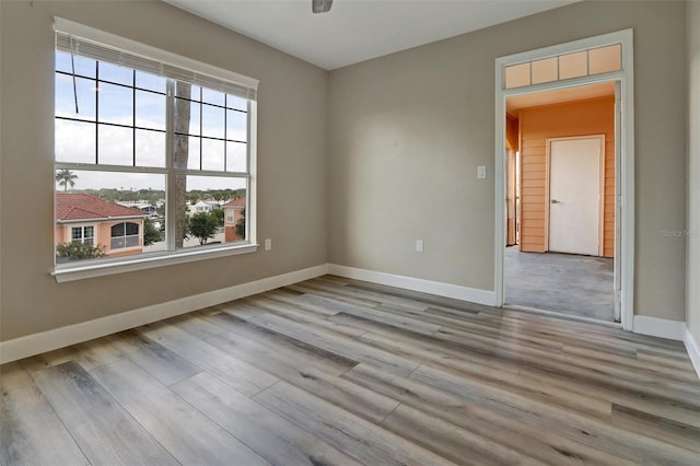 empty room with wood finished floors, a ceiling fan, and baseboards