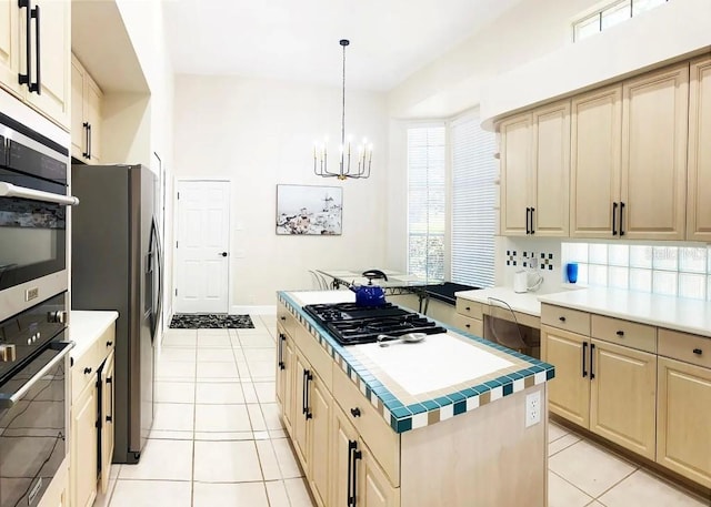 kitchen featuring an inviting chandelier, decorative light fixtures, appliances with stainless steel finishes, a center island, and light tile patterned flooring