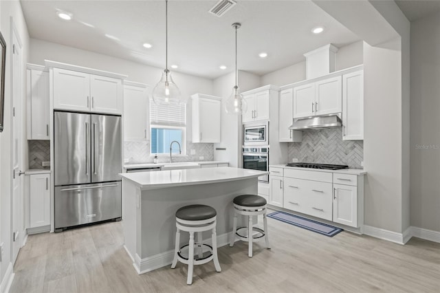 kitchen featuring light countertops, under cabinet range hood, visible vents, white cabinets, and appliances with stainless steel finishes