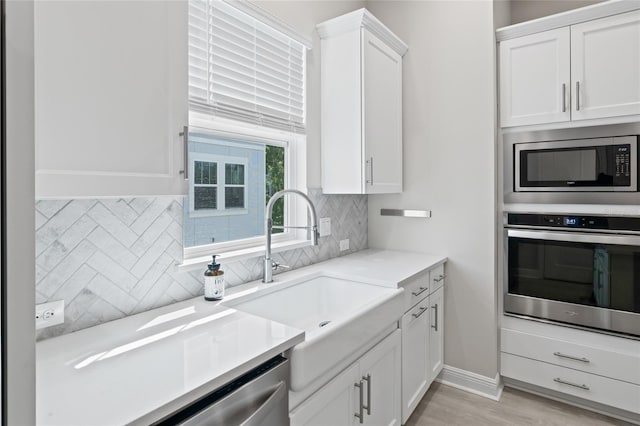 kitchen with white cabinets, a sink, stainless steel appliances, and backsplash
