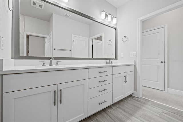 bathroom featuring double vanity, a sink, wood finished floors, and visible vents