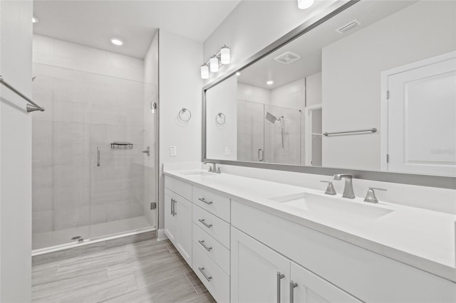bathroom featuring double vanity, a sink, a stall shower, and visible vents