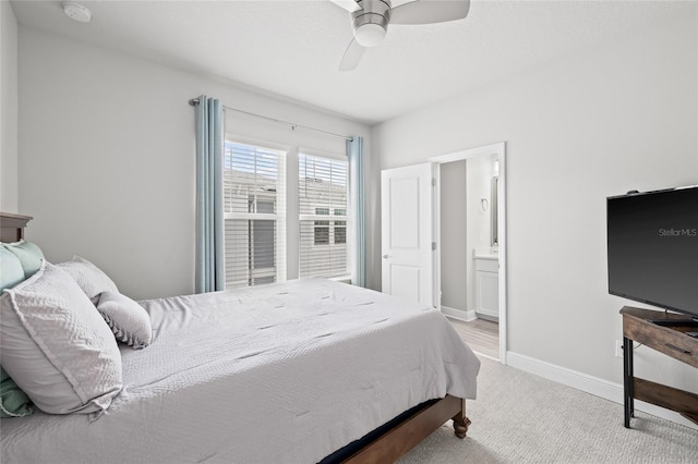 carpeted bedroom featuring baseboards, ensuite bath, and a ceiling fan