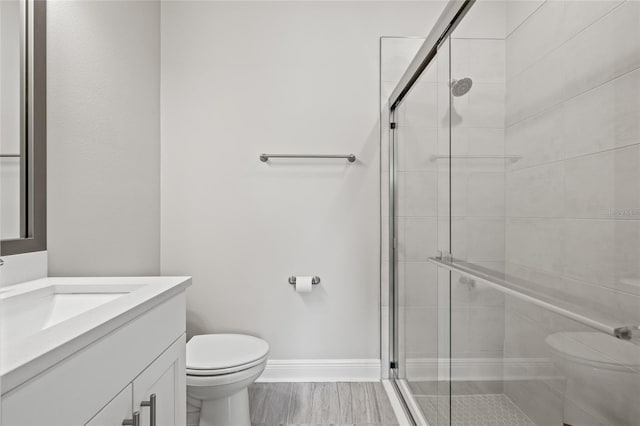 bathroom with toilet, wood finished floors, and a shower stall