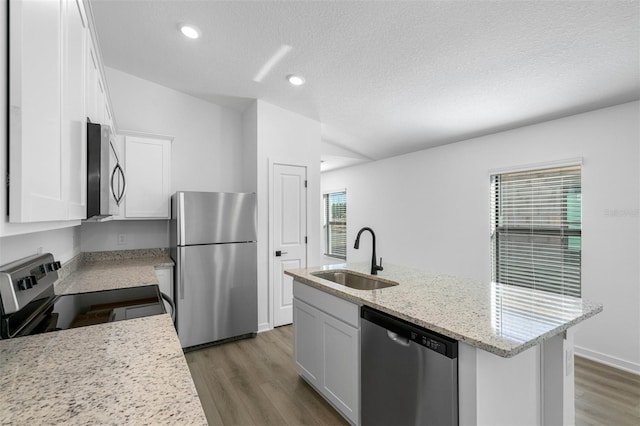 kitchen featuring a center island with sink, a sink, wood finished floors, white cabinetry, and stainless steel appliances