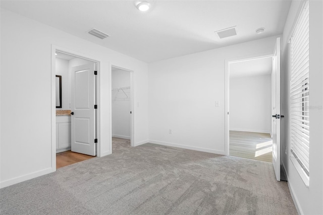 unfurnished bedroom with multiple windows, a spacious closet, and light colored carpet