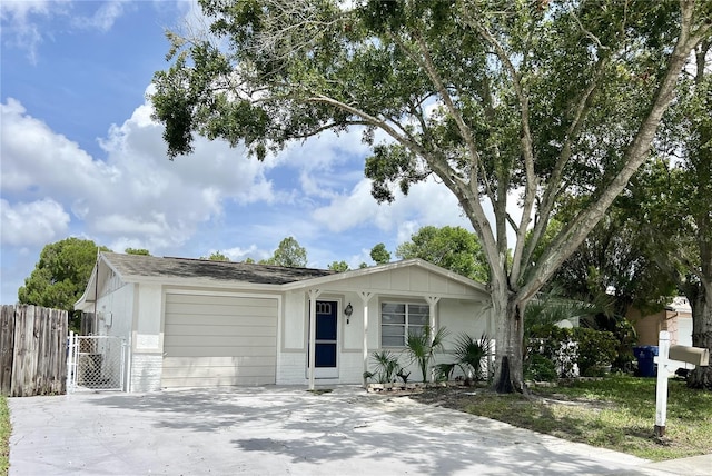 ranch-style home with concrete driveway, a gate, an attached garage, and fence