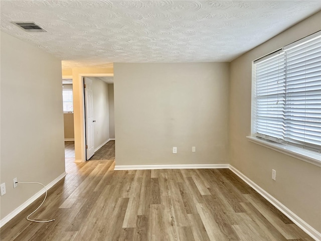 spare room with a textured ceiling and hardwood / wood-style floors