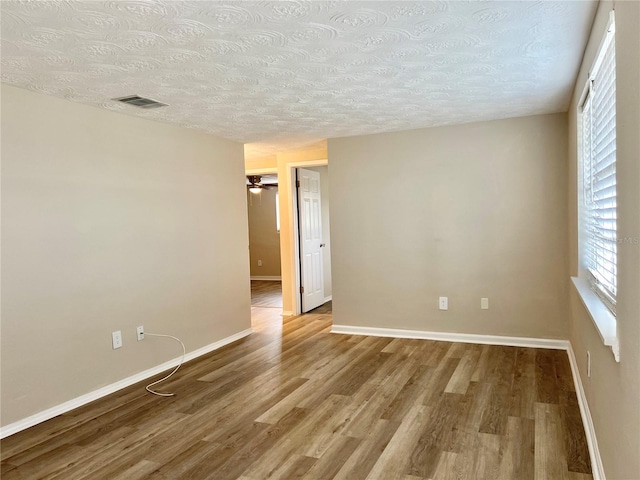 unfurnished room with a textured ceiling and wood-type flooring