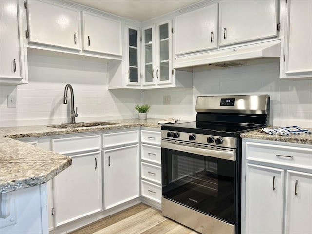 kitchen with stainless steel stove, light hardwood / wood-style floors, sink, white cabinetry, and light stone counters