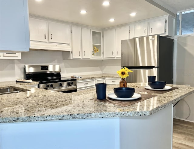 kitchen featuring white cabinets, light wood-type flooring, appliances with stainless steel finishes, light stone countertops, and sink