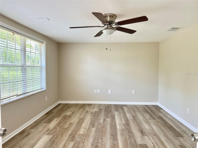 empty room with ceiling fan, a textured ceiling, and light hardwood / wood-style flooring