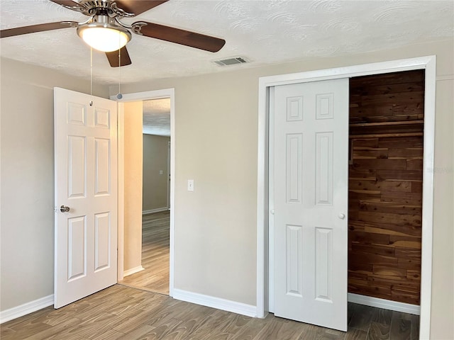 unfurnished bedroom featuring a textured ceiling, a closet, ceiling fan, and hardwood / wood-style floors