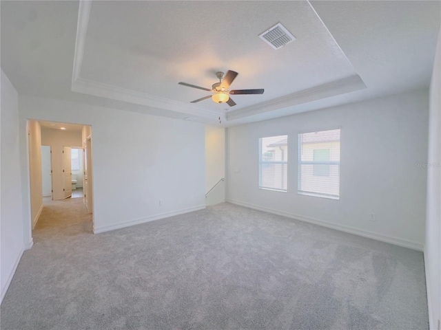 carpeted empty room with a tray ceiling and ceiling fan