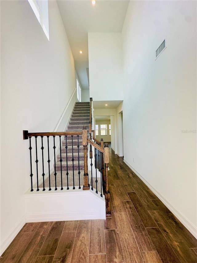 stairway with a towering ceiling and hardwood / wood-style flooring