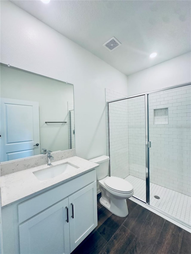 bathroom featuring an enclosed shower, hardwood / wood-style flooring, vanity, and toilet