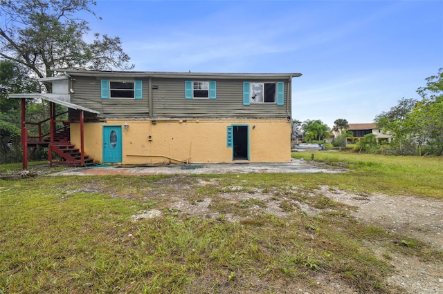 rear view of property with stairway and a yard