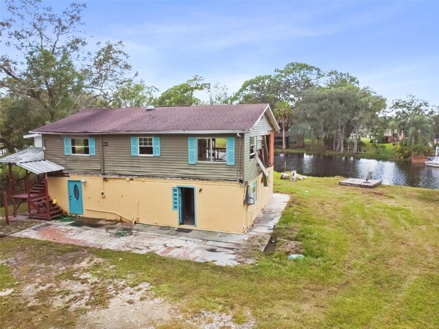 back of house featuring a water view and a lawn