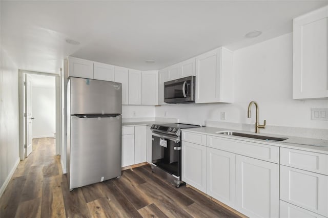 kitchen featuring light countertops, appliances with stainless steel finishes, dark wood-style floors, white cabinetry, and a sink