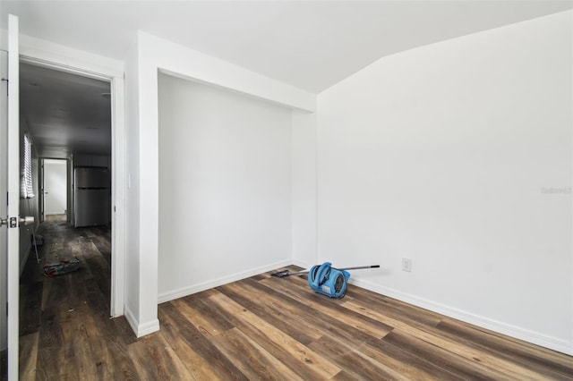 unfurnished room featuring vaulted ceiling, baseboards, and wood finished floors