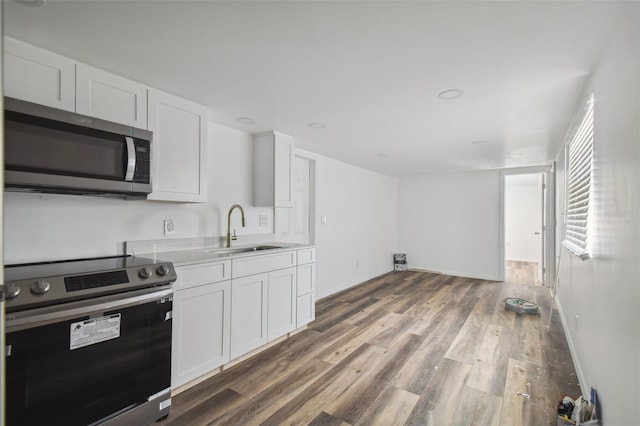 kitchen with wood finished floors, a sink, light countertops, white cabinets, and appliances with stainless steel finishes