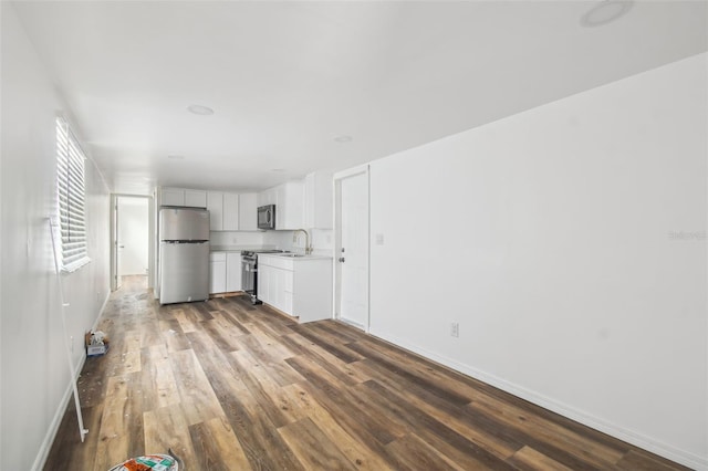 kitchen with baseboards, dark wood finished floors, a sink, light countertops, and appliances with stainless steel finishes