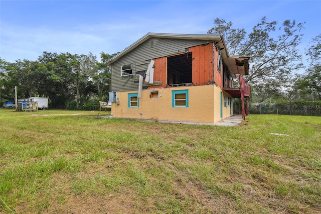 view of side of home with a yard, fence, and stucco siding