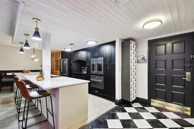 kitchen featuring light wood-type flooring, a kitchen breakfast bar, wood ceiling, and stainless steel refrigerator